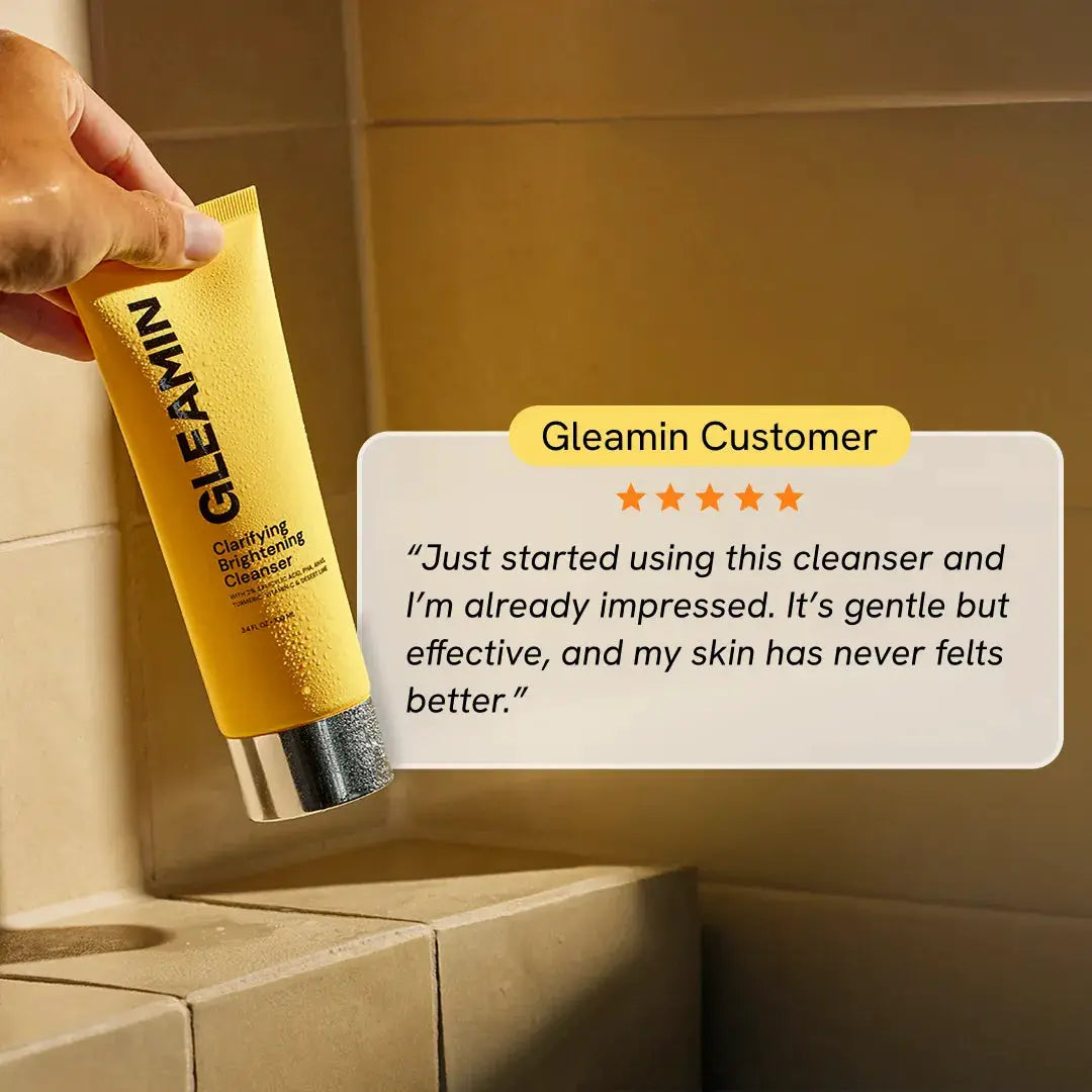 Facial cleanser Gleamin Clarifying Brightening Cleanser in a yellow tube, held in hand.