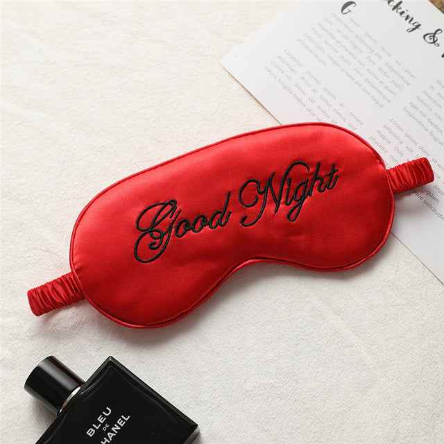 Eye mask and Bleu de Chanel perfume bottle; red silk eye mask with black Good Night embroidery