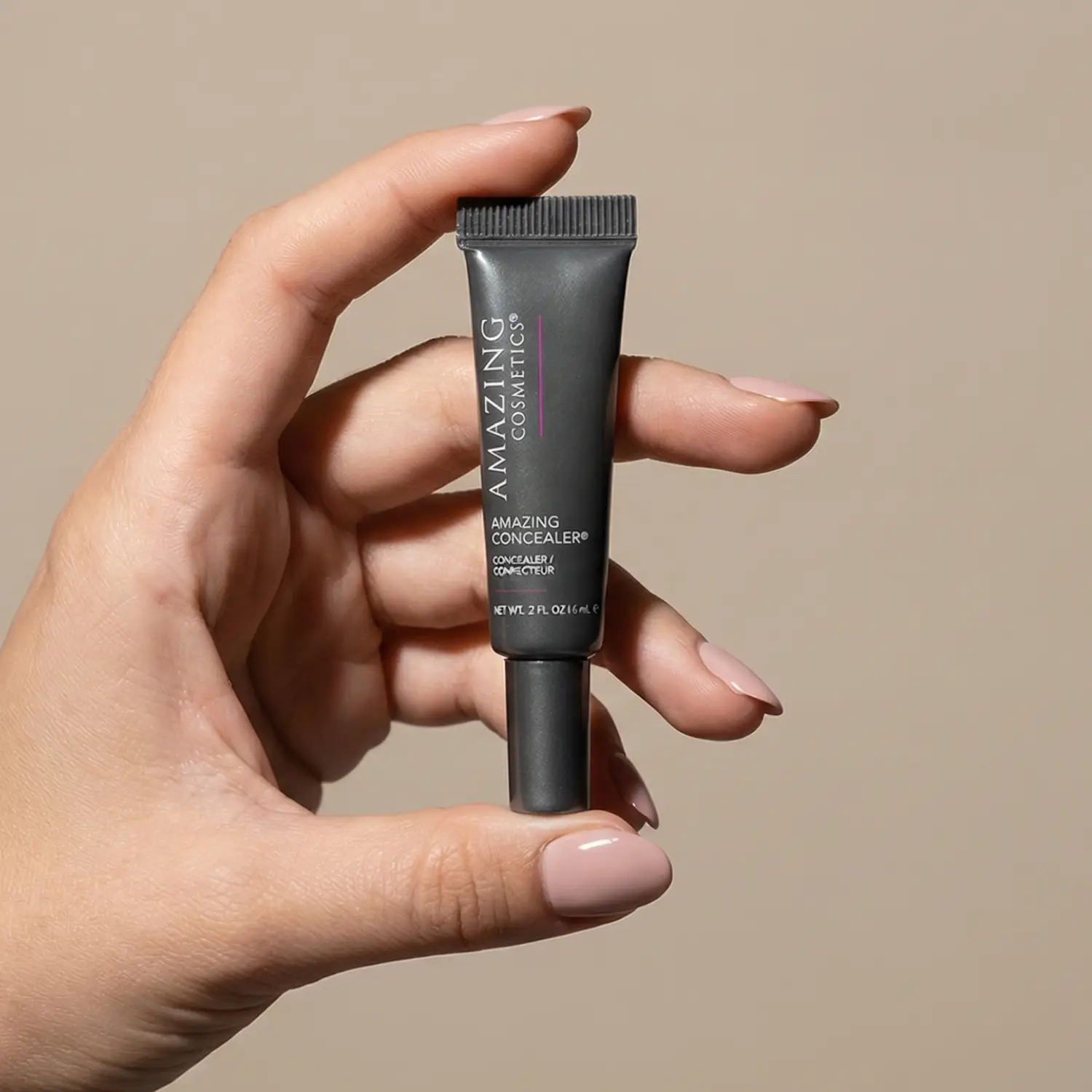 AMAZINGCONCEALER tube by AmazingCosmetics in dark gray packaging held in hand